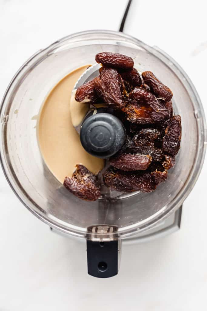 a food processor with dates, tahini and salt in it