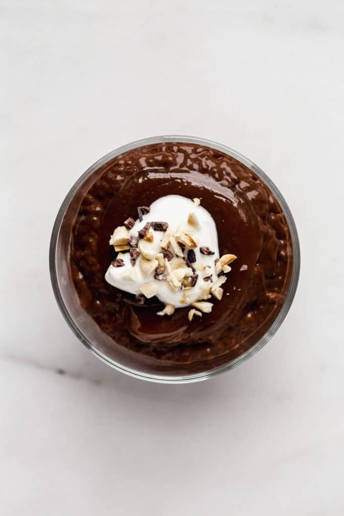 a top down view of chocolate chia pudding in a cup topped with yogurt