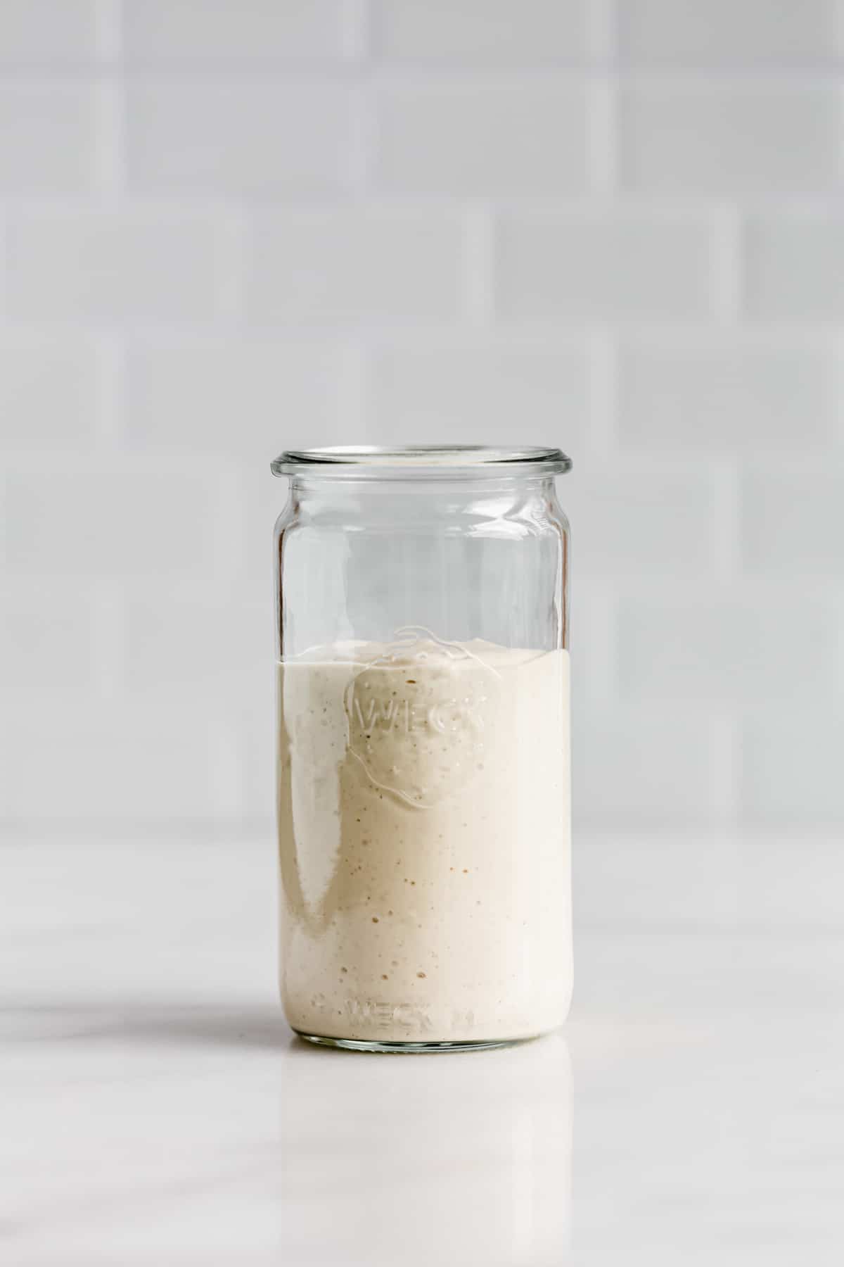A jar of vegan caesar salad dressing on a white counter
