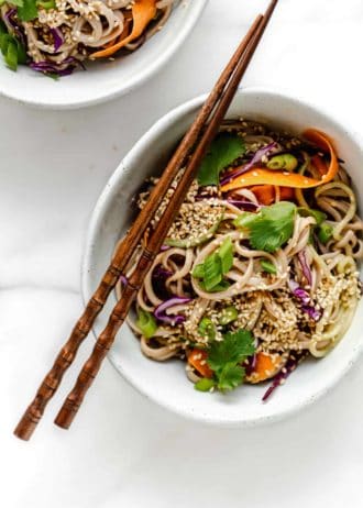 A bowl of soba noodle salad with vegetables topped with cilantro