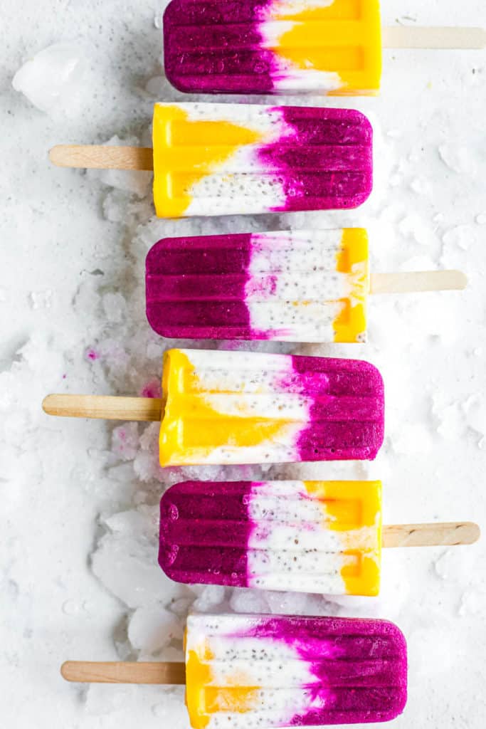 6 tropical coconut chia popsicles with layers of mango, coconut and dragonfruit