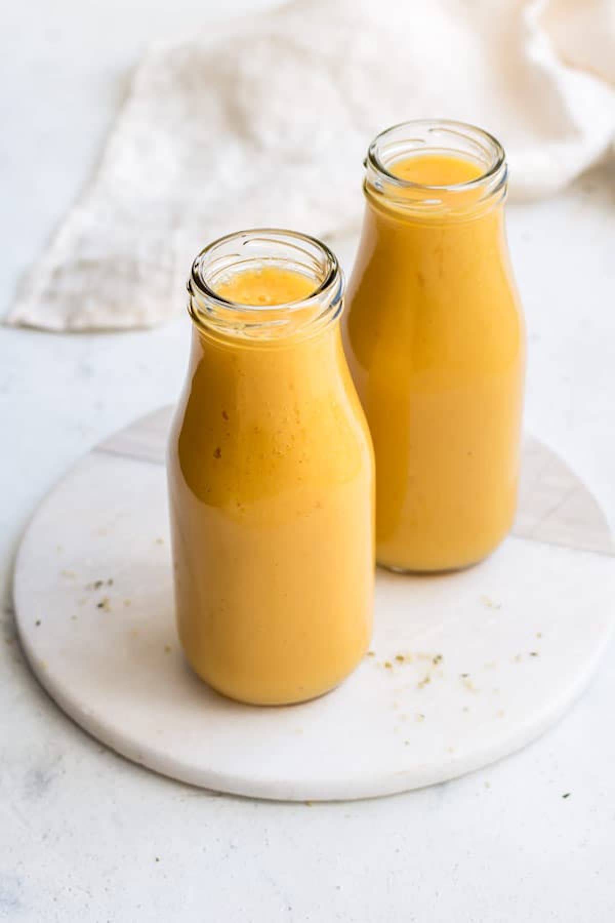 two tall glasses of a bright yellow mango smoothie made from healthy smoothie recipes to make your insides glow