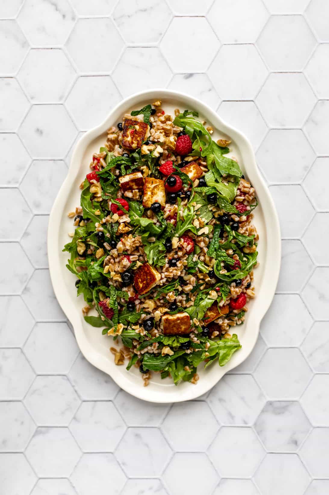 A white serving platter with farro and halloumi salad on it