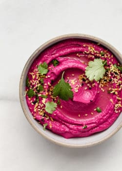 Roasted Beet Hummus in a bowl topped with cilantro and sesame seeds