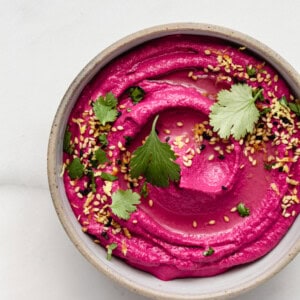 Roasted Beet Hummus in a bowl topped with cilantro and sesame seeds