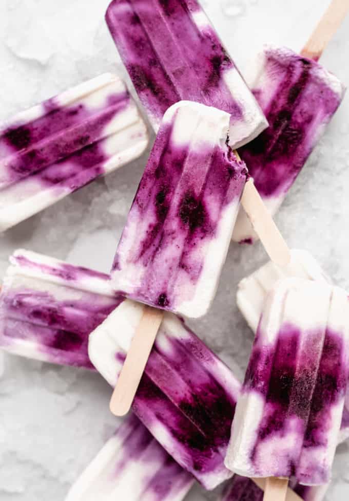 a blueberry greek yogurt popsicle with a bite taken out of it