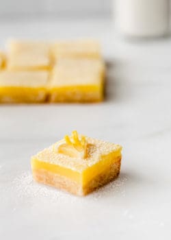 a lemon square topped with a slice of lemon on a marble board