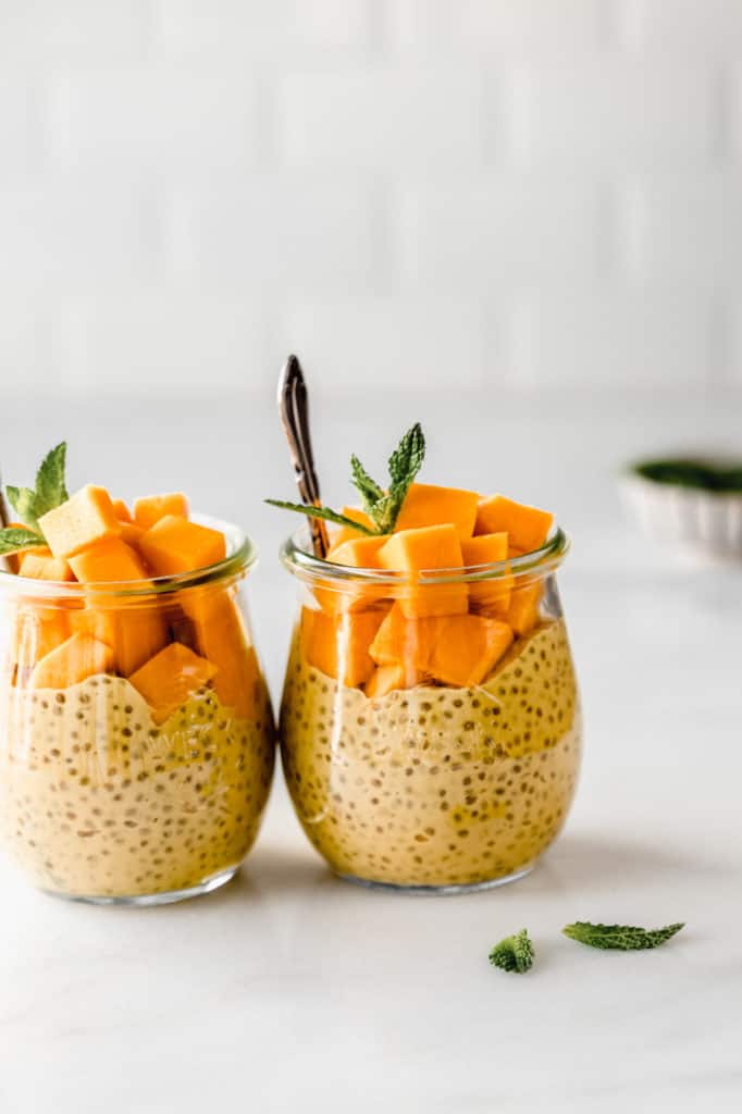 Two small jars of mango chia pudding topped with cubes of mango