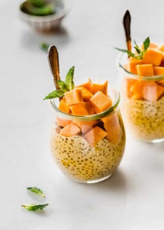 a jar filled with mango chia pudding, cubed mangos and fresh mint