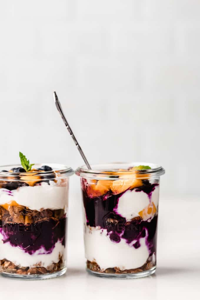 two jars of yogurt and granola parfait with blueberry and mango