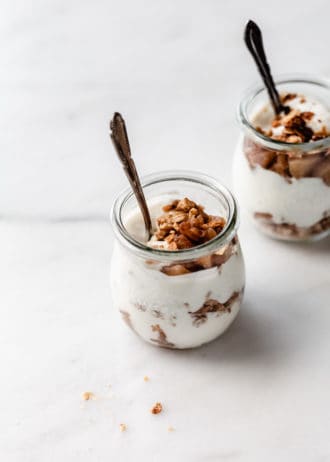two jars of apple pie parfaits with spoons in them