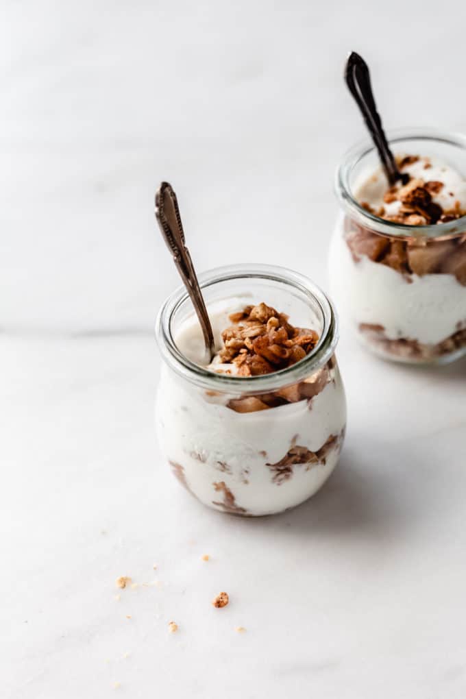 two jars of apple pie parfaits with spoons in them