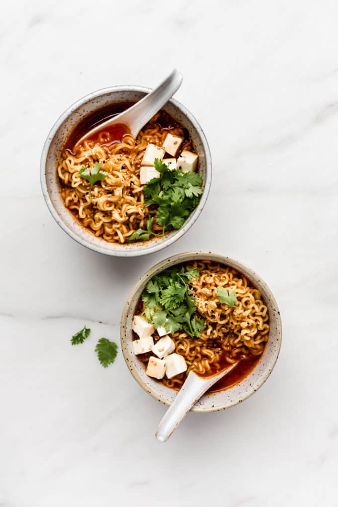 two bowls of ramen with noodles, tofu and cilantro