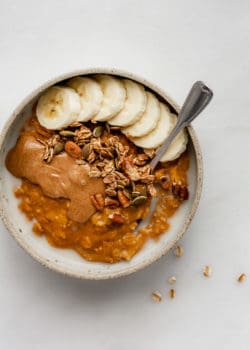 pumpkin oatmeal in a bowl topped with bananas and granola