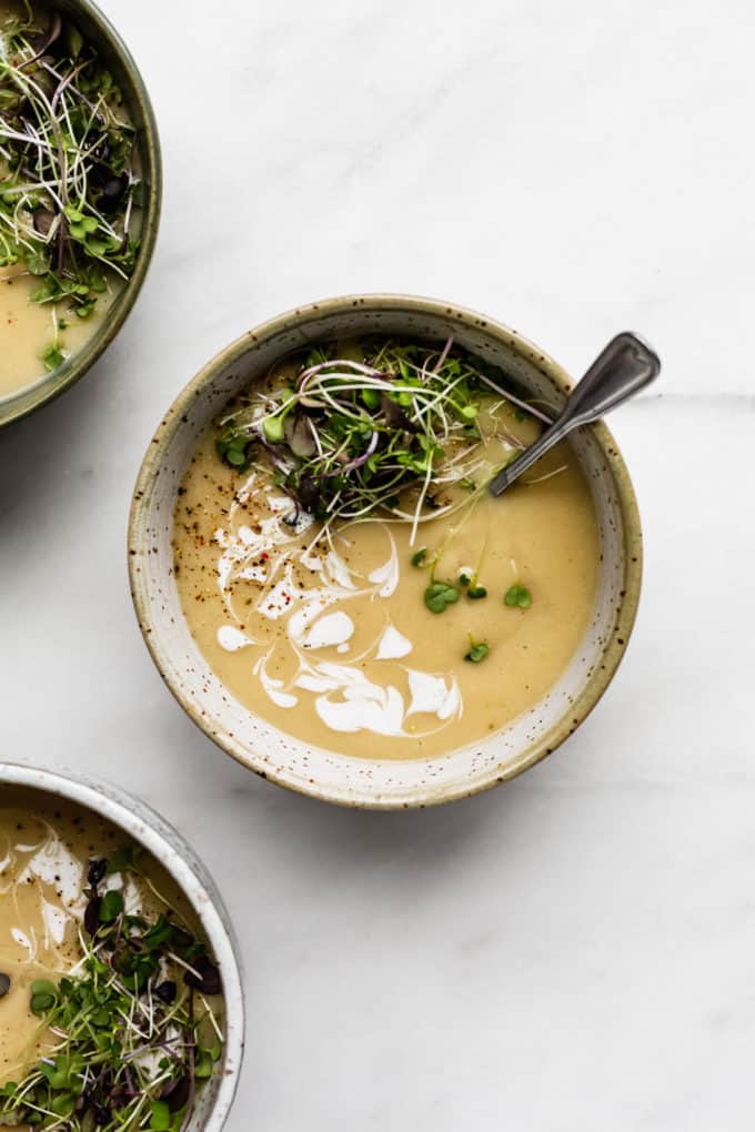 a bowl of roasted garlic soup topped with radish sprouts