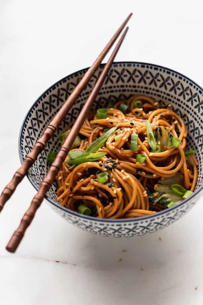 a bowl of noodles topped with green onions and sesame seeds