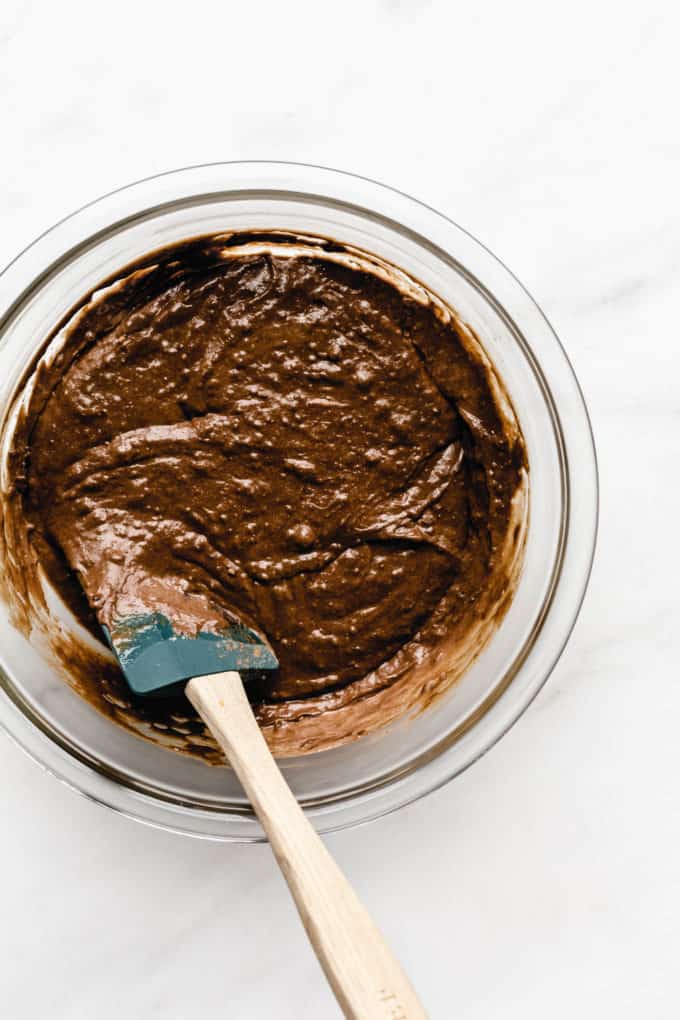 A mixing bowl of chocolate pumpkin bread batter with a spatula in it