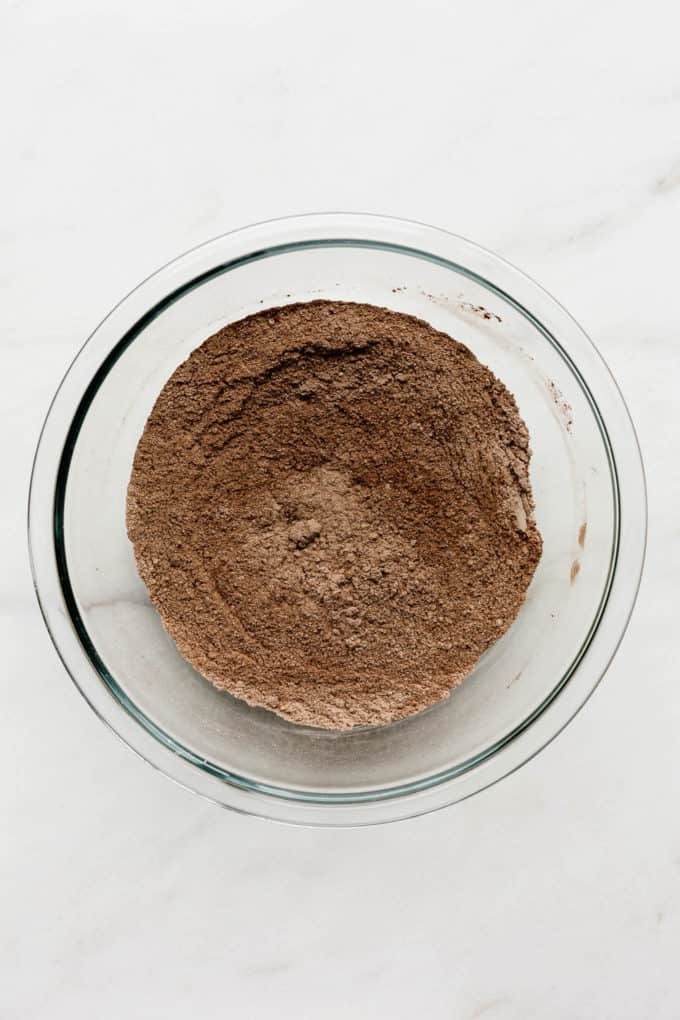 A clear mixing bowl with flour and cocoa powder in it