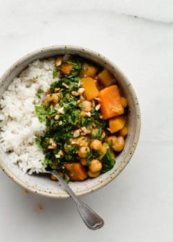 A bowl of pumpkin chickpea curry and rice with a spoon in it