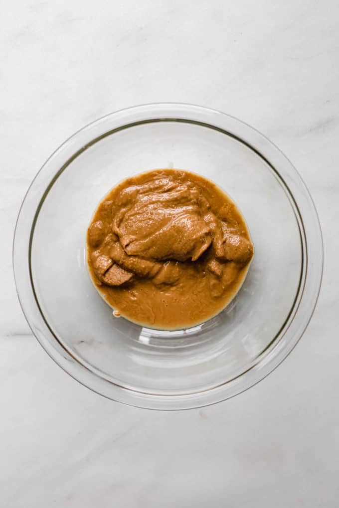 A clear mixing bowl with peanut butter in it