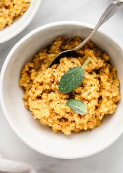 A bowl of butternut squash risotto topped with sage leaves