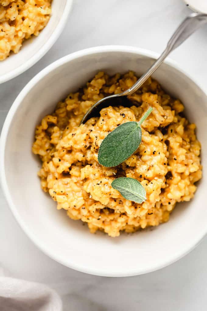 A bowl of butternut squash risotto topped with sage leaves