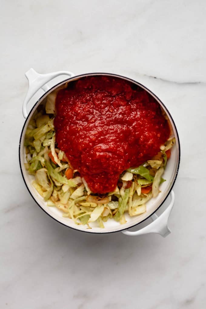 shredded cabbage, vegetables and crushed tomatoes in a white pot