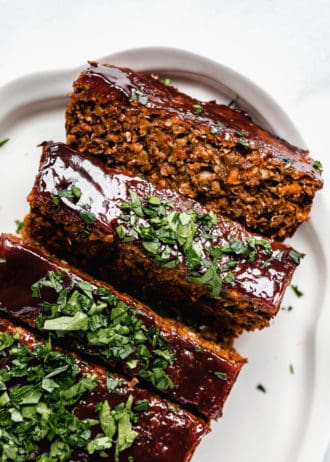 lentil loaf sliced on a white serving platter topped with chopped parsley