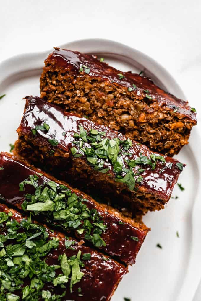 lentil loaf sliced on a white serving platter topped with chopped parsley