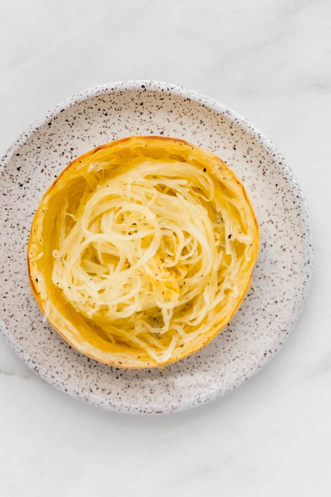 a ring of spaghetti squash on a white speckled plate