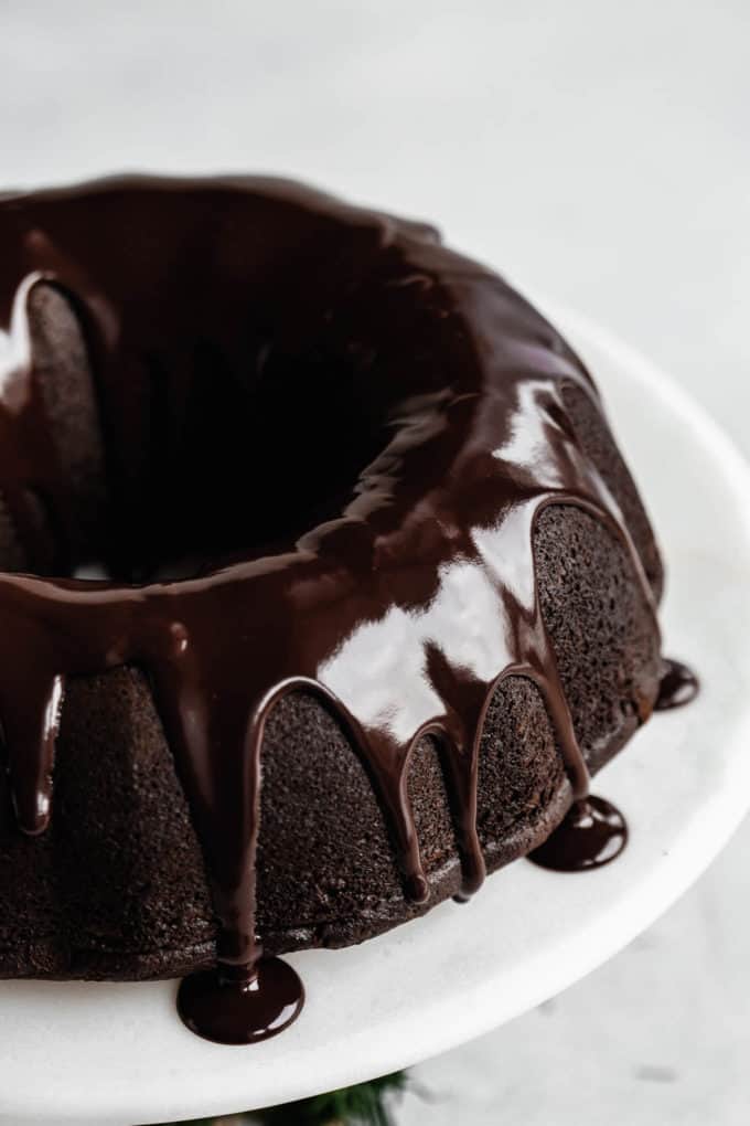 A close up of a gingerbread bundt cake with chocolate glaze dripping down the sides