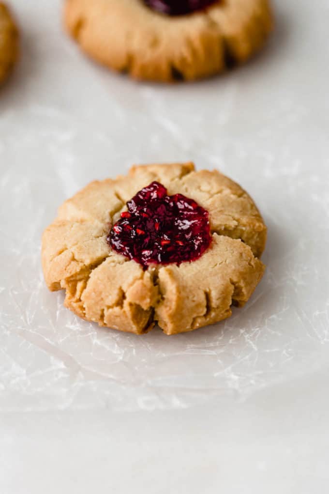 A raspberry thumbprint cookie on a piece of wax paper