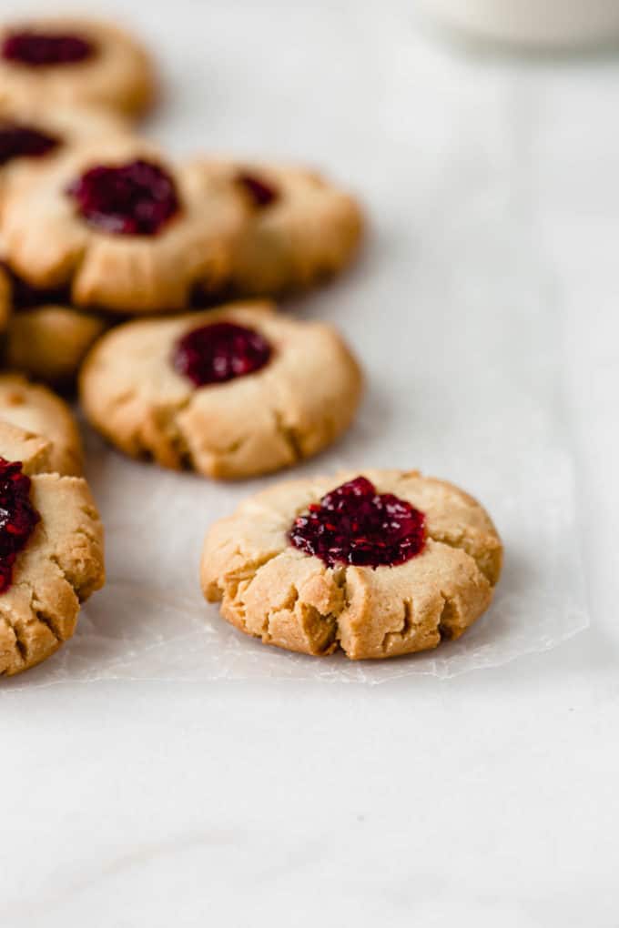 A pile of raspberry thumbprint cookies on some wax paper