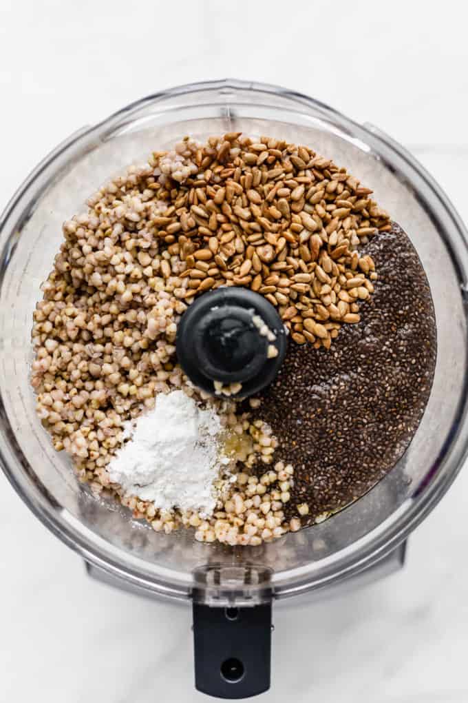 a food processor with buckwheat groats, chia seed gel, sunflower seeds and baking powder in it