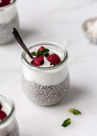 A cup of chia seed pudding topped with yogurt and raspberries