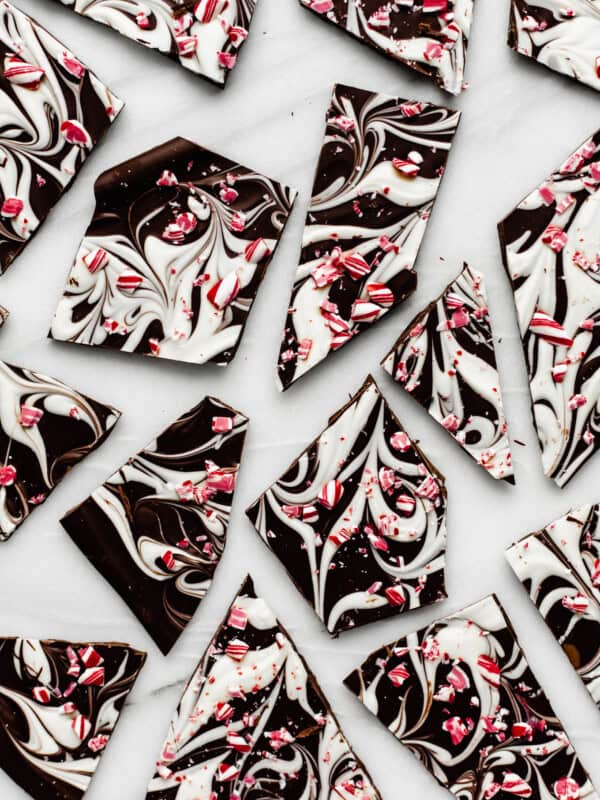 peppermint bark broken up on a marble tray with crushed candy canes on top