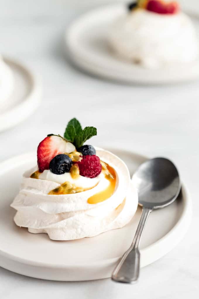a mini pavlova on a white plate with a spoon in the side