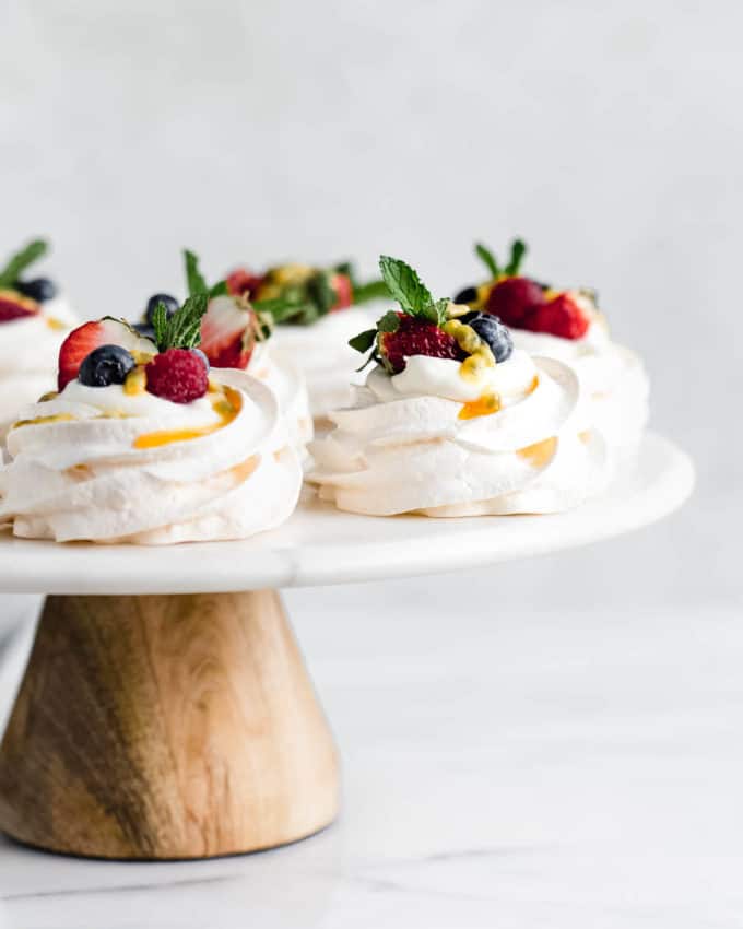 mini pavlovas on a marble and wood cake stand
