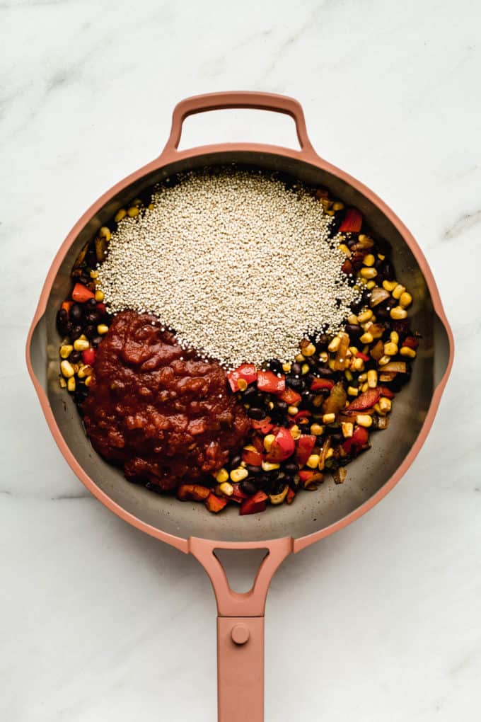A pink pan with beans, corn, quinoa and salsa in it