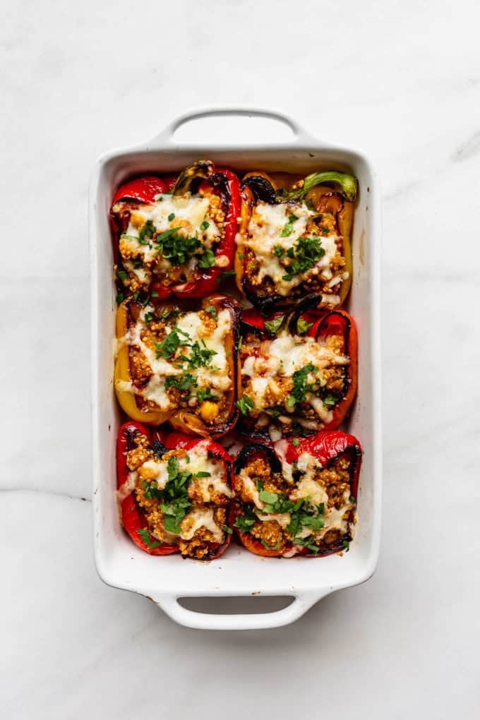 a white baking dish with 6 quinoa stuffed peppers in it