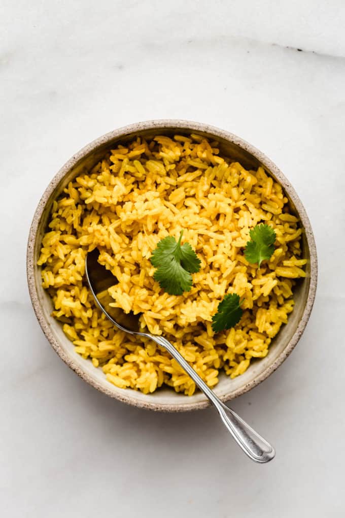 A bowl of turmeric rice with a spoon in it