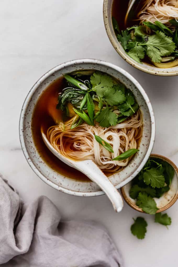 A bowl of vegan pho soup with rice noodles, cilantro and green onions
