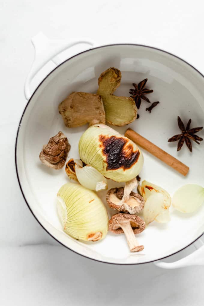 Onions, dried shitake, cinnamon, star anise and ginger in a white pot