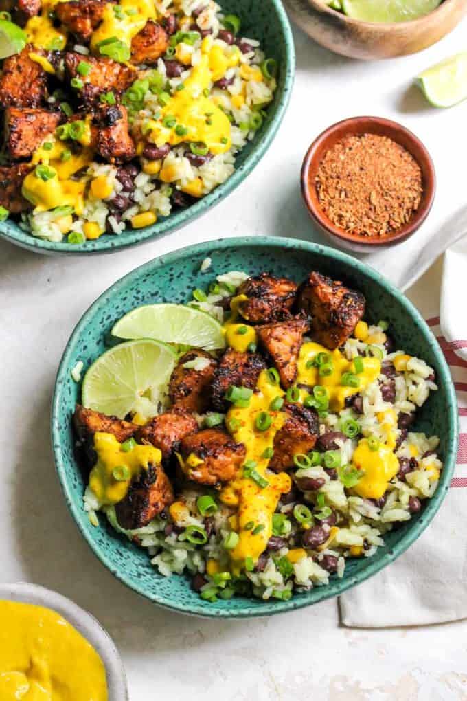 A Turquoise bowl with tempeh, rice and yellow sauce in it