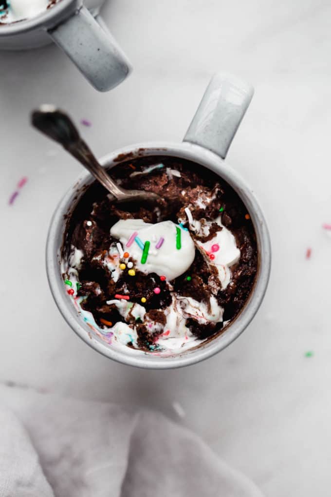 A chocolate mug cake with whipped cream and sprinkles on top