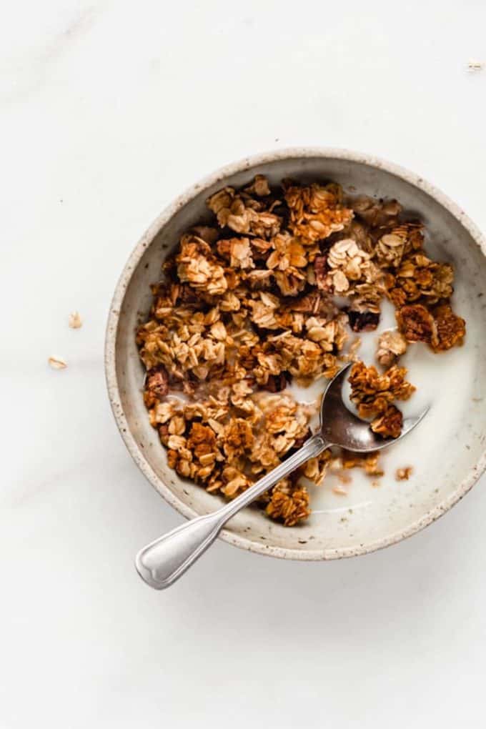 A bowl with banana granola and almond milk in it 