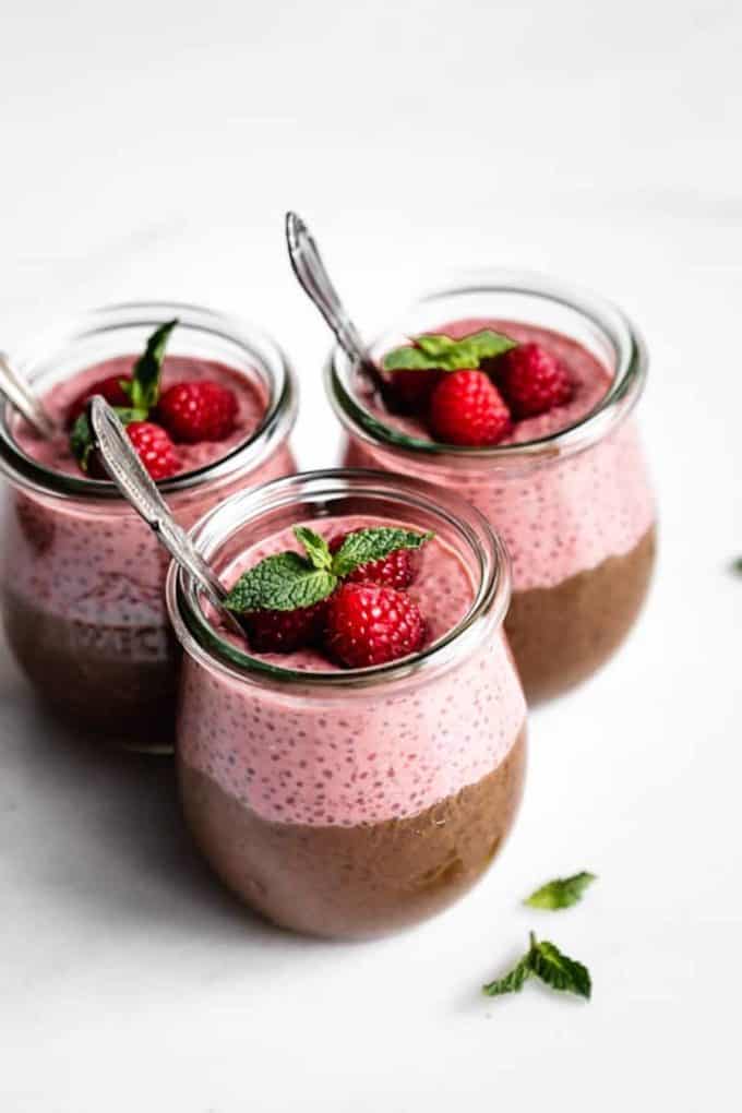 three jars with chocolate raspberry chia pudding topped with raspberries