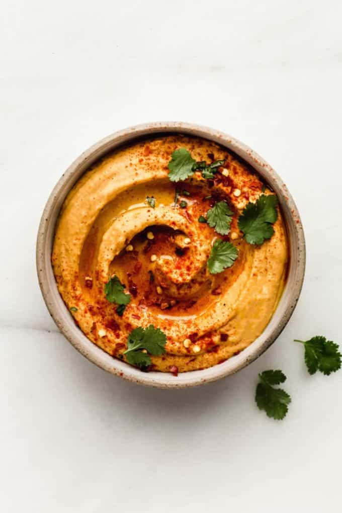 A bowl with sweet potato hummus topped with paprika and cilantro