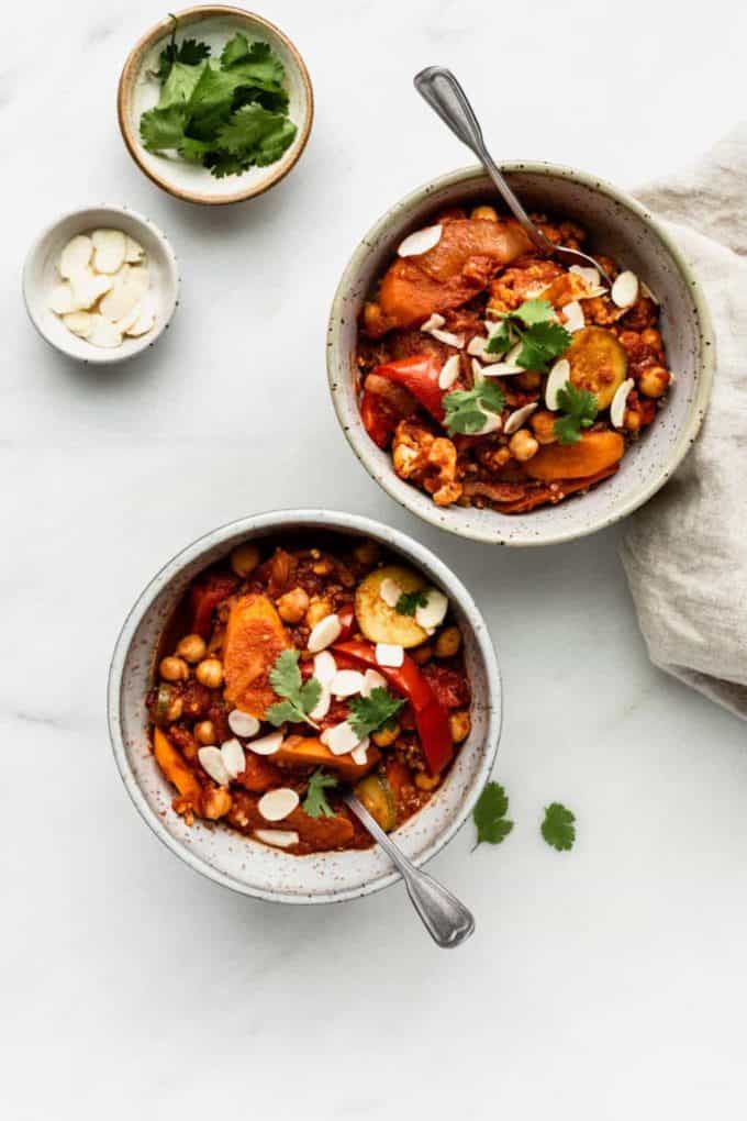 Two bowls of vegetable Tagine with a side of parsley and almonds