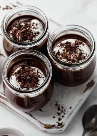 three small jars filled with chocolate topped with shredded dark chocolate